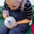Rhian Malin decorating a mandala bottle in her workshop 2019